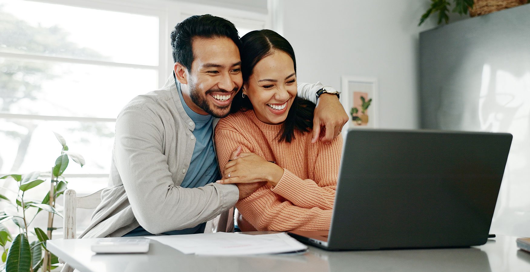 Couple smiling at their computer. 