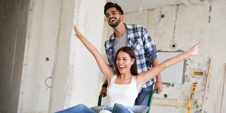 Man and woman smiling, doing home renovations.