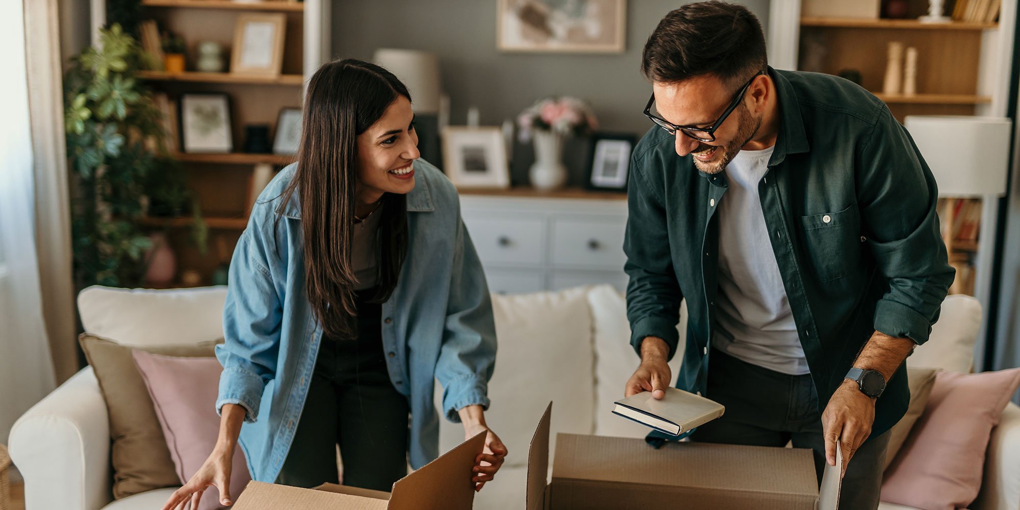 Smiling couple unpacking boxes together in a cozy living room.